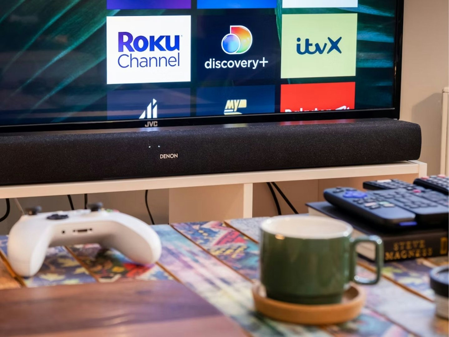 A Denon soundbar in front of a coffee table next to a TV