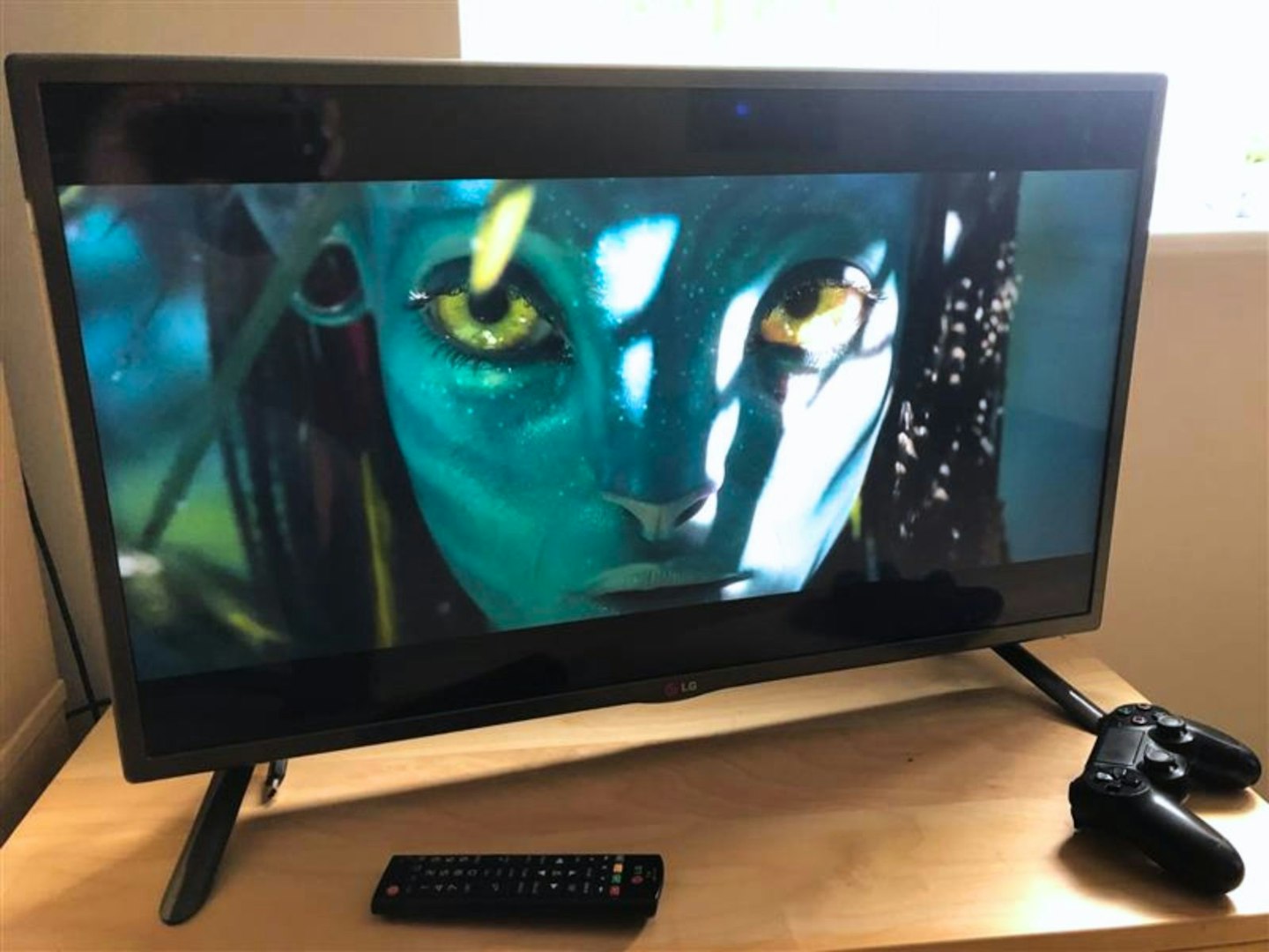 A 32-inch TG TV with Avatar on the screen and a playstation controller