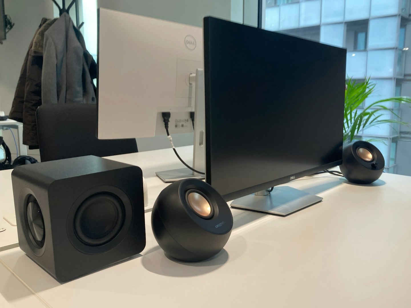 Speakers for monitors. The Creative Pebble X Plus speakers and subwoofer pictured on desk with PC monitor and plant in background.