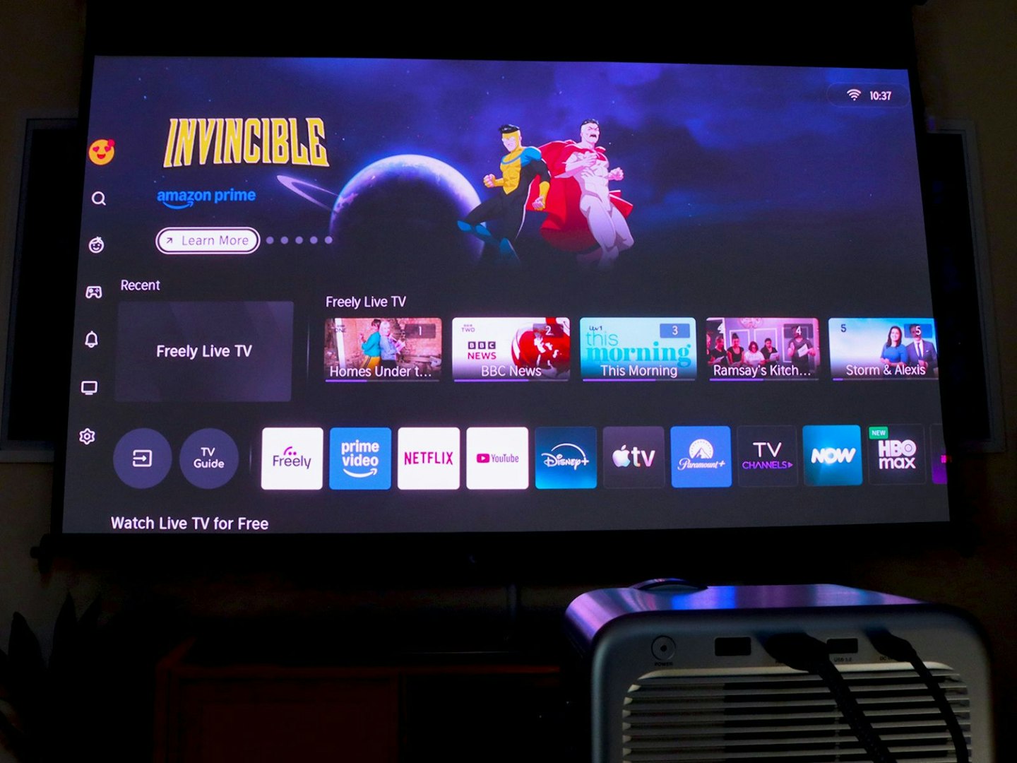 Hisense M2 Pro projector and popcorn on a table - projecting Android TV home page with Invincible
