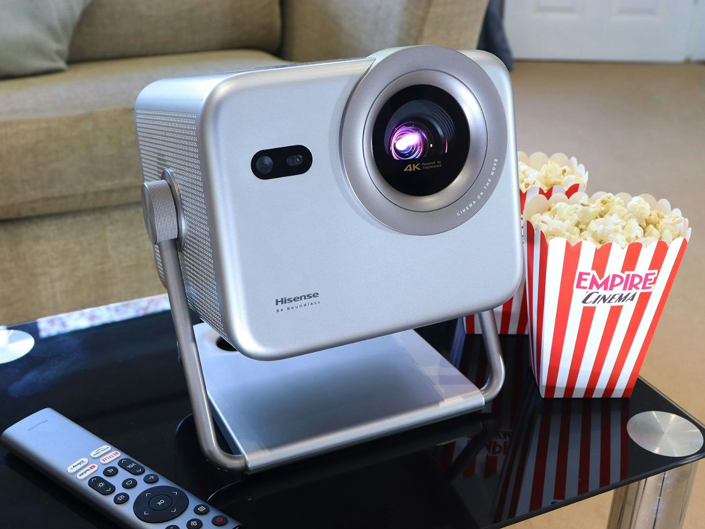 Hisense M2 Pro projector on a table in a lounge with remote and popcorn