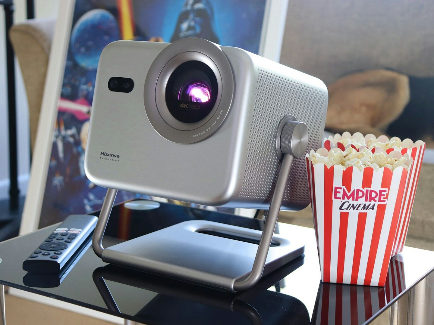 Hisense M2 Pro projector on a table in a lounge with remote and popcorn