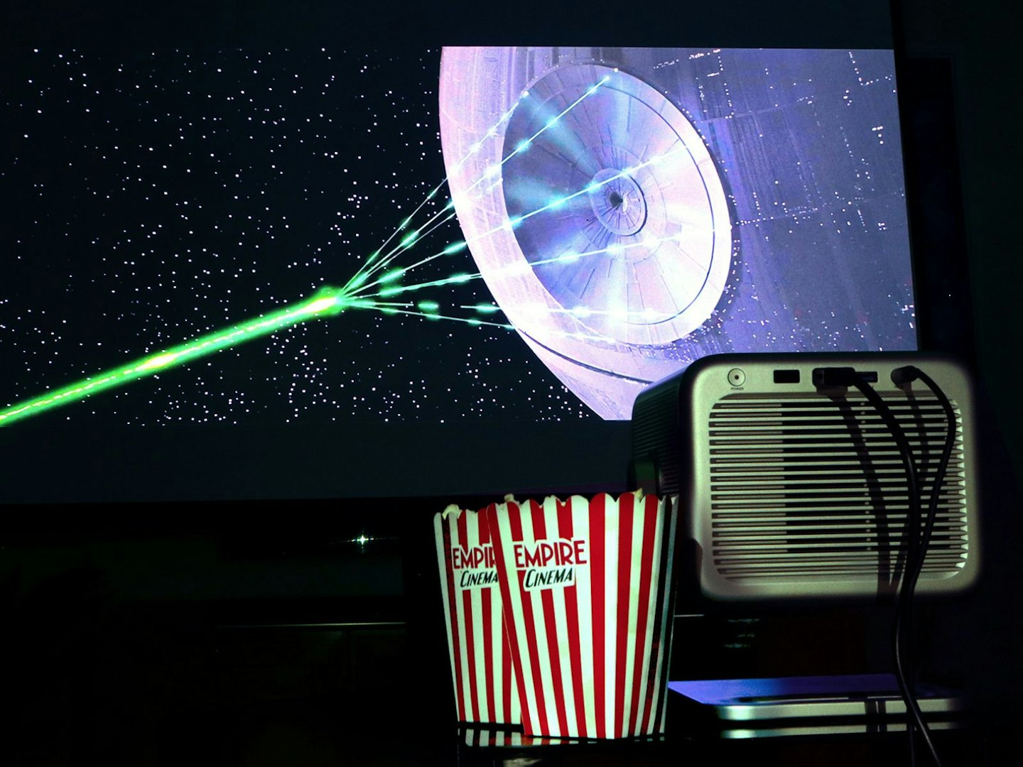 Hisense M2 Pro projector and popcorn on a table - projecting Death Star from Star Wars